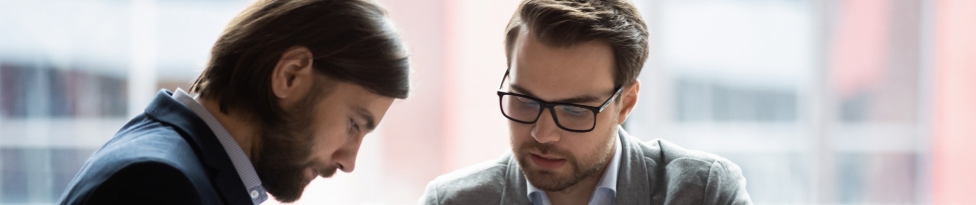 Gefocuste jonge zakenman tekent een document waar de financiële man aanwijst waar te tekenen